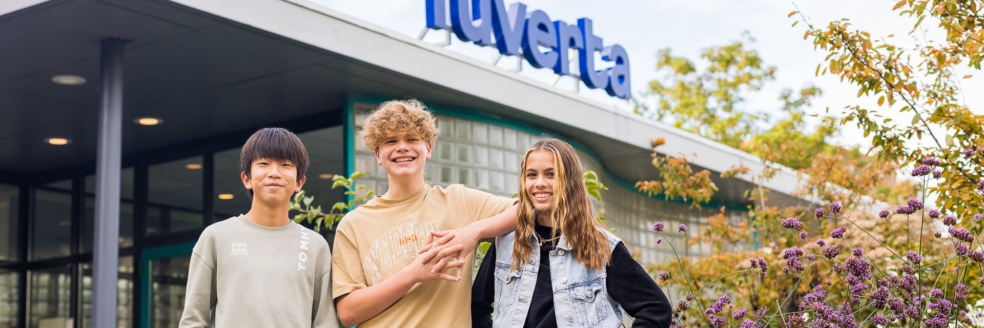 Drie leerlingen staan voor het schoolgebouw van Yuverta Gouda