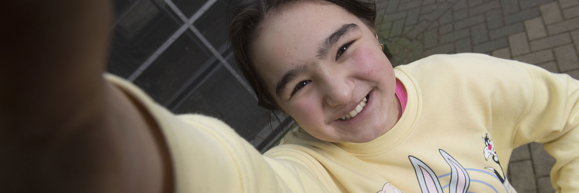 een leerling kijkt lachend naar de camera