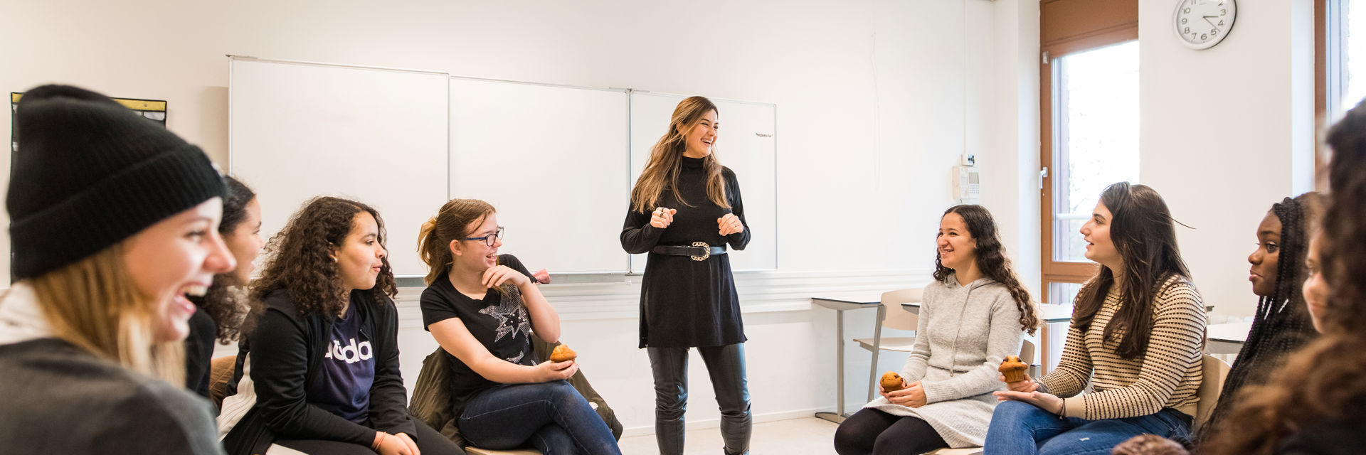 Docent leidt groep lachende studenten in klaslokaal