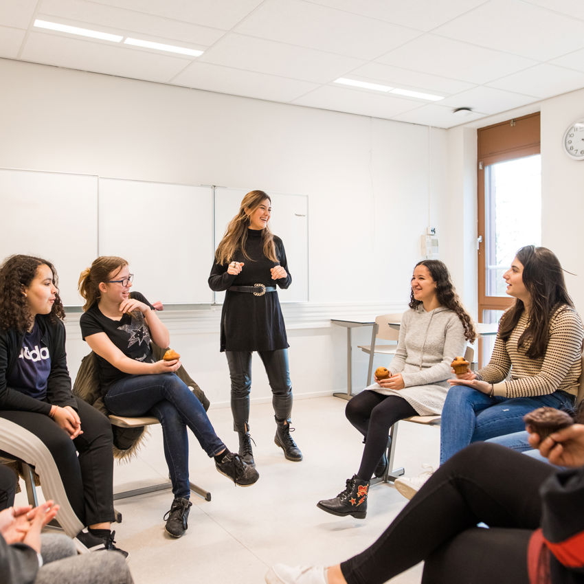 Docent leidt groep lachende studenten in klaslokaal