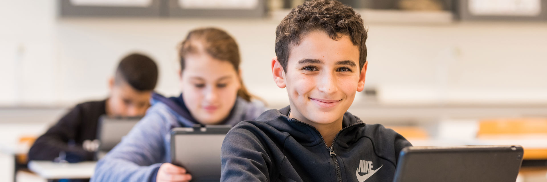 Een blije leerling werkt met een tablet