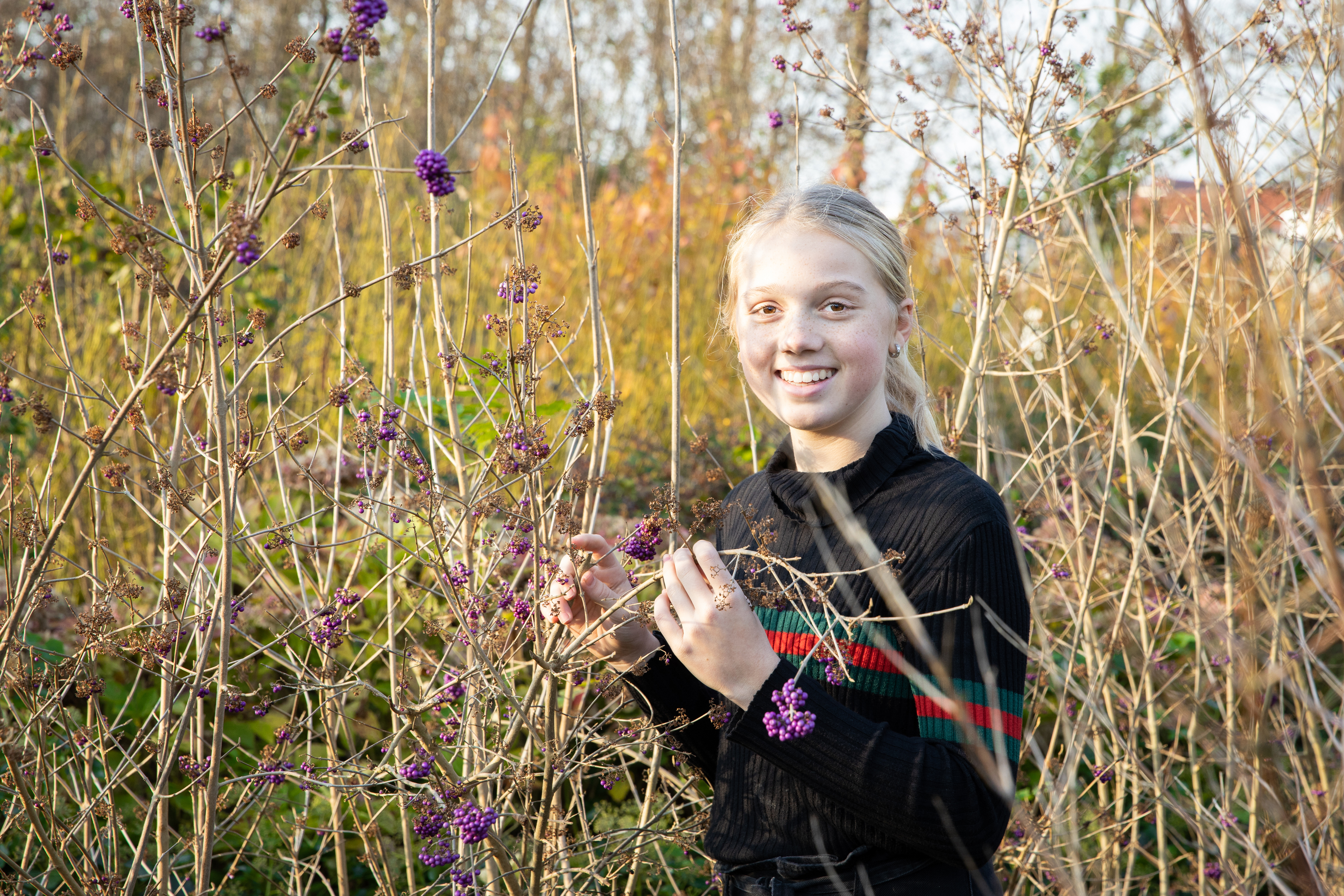 Een leerling staat buiten tussen de planten