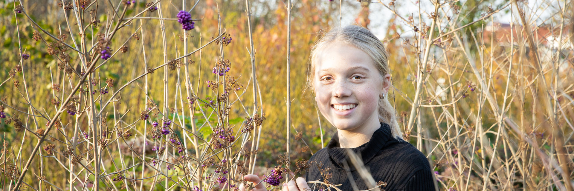 Een leerling staat buiten tussen de planten