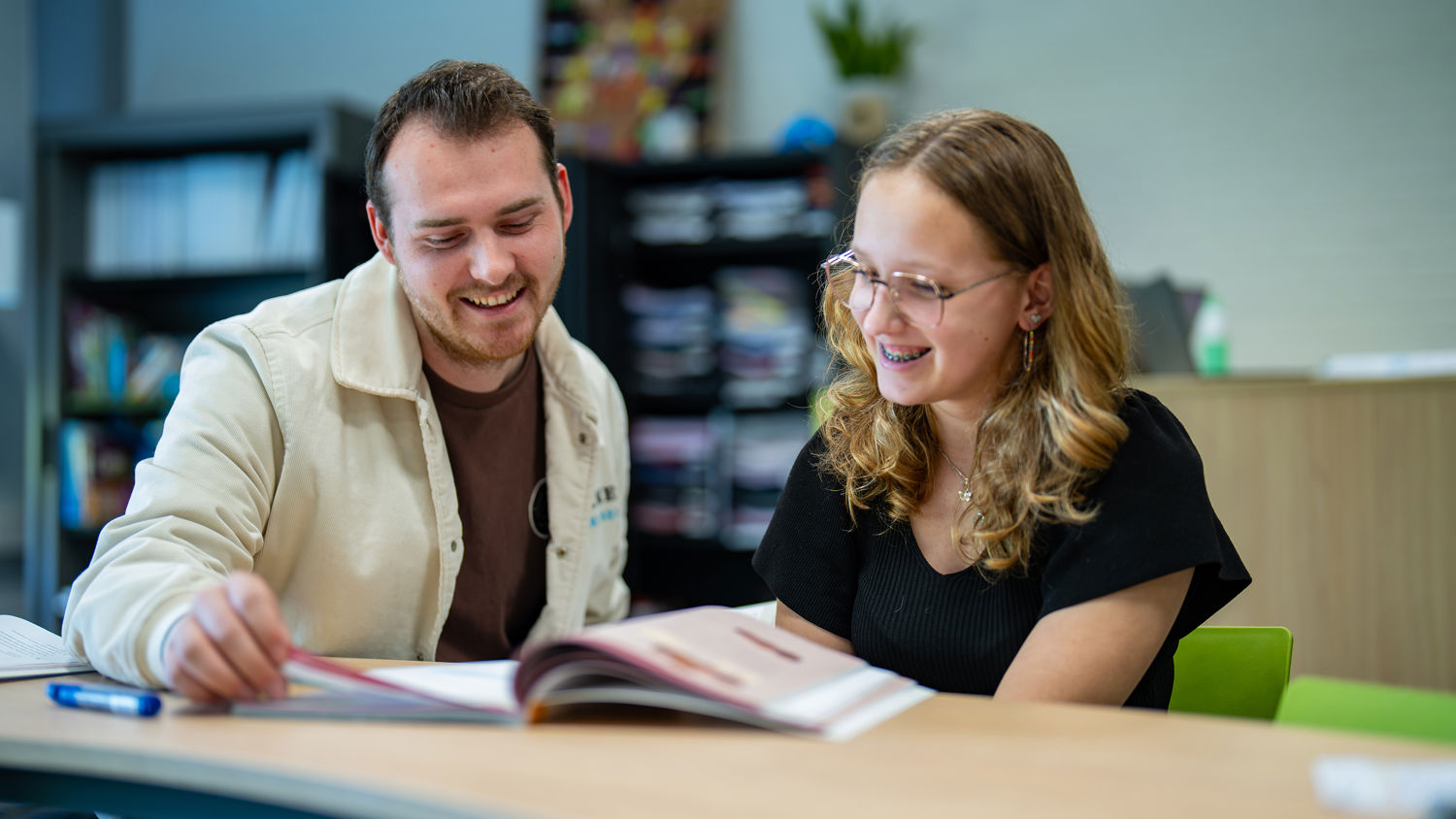 Docent leidt groep lachende studenten in klaslokaal