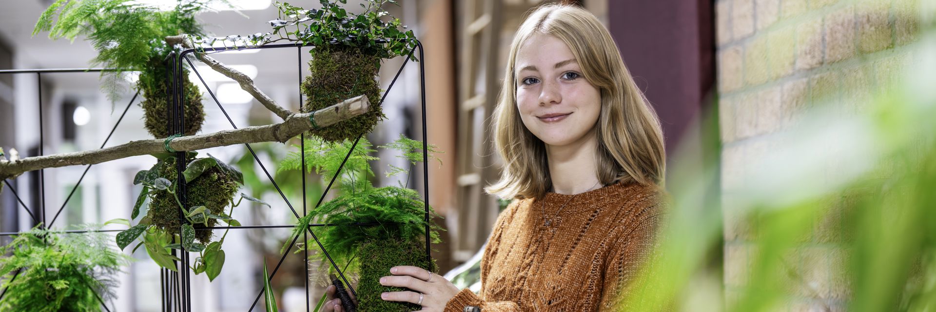 Een student werkt aan een planten display