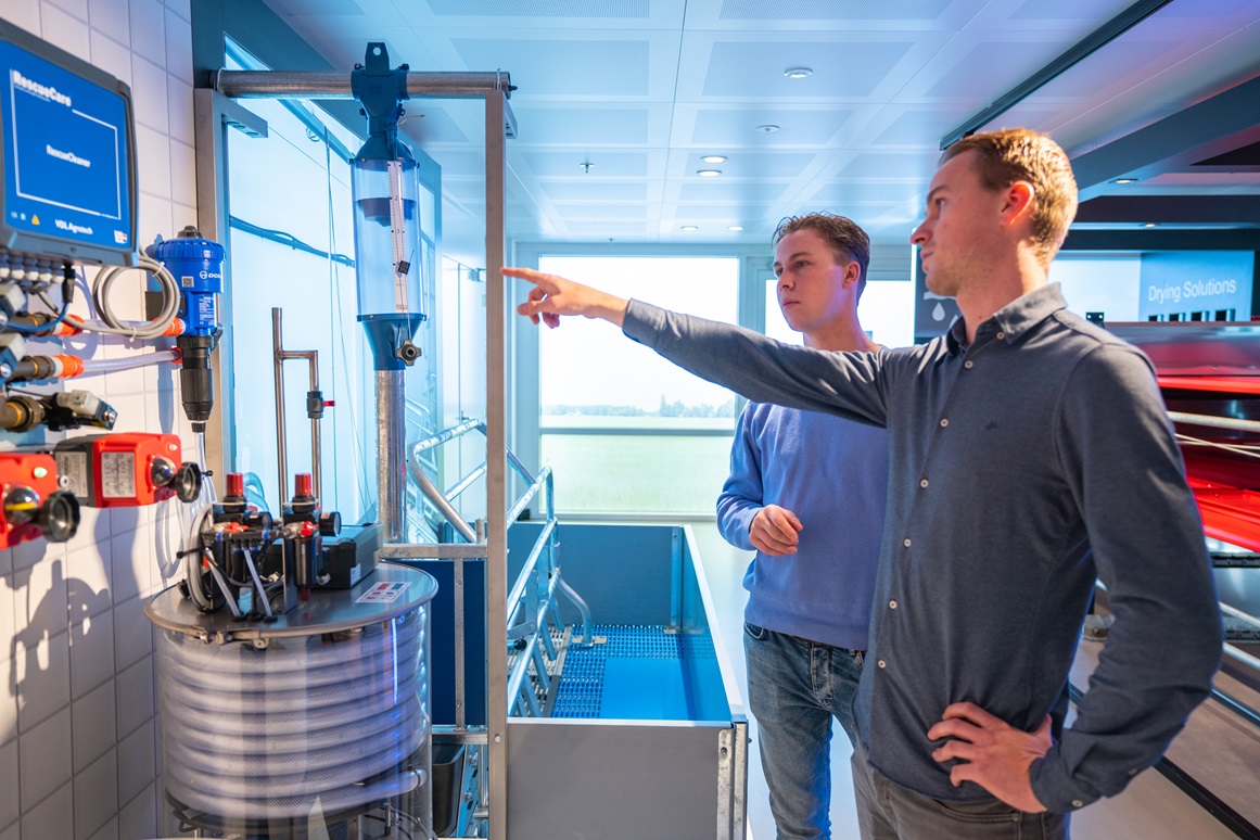 Docent leidt groep lachende studenten in klaslokaal