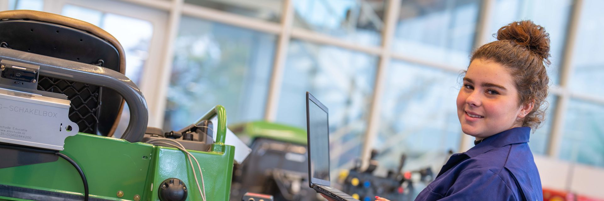 Een student werkt met een laptop aan een tractor