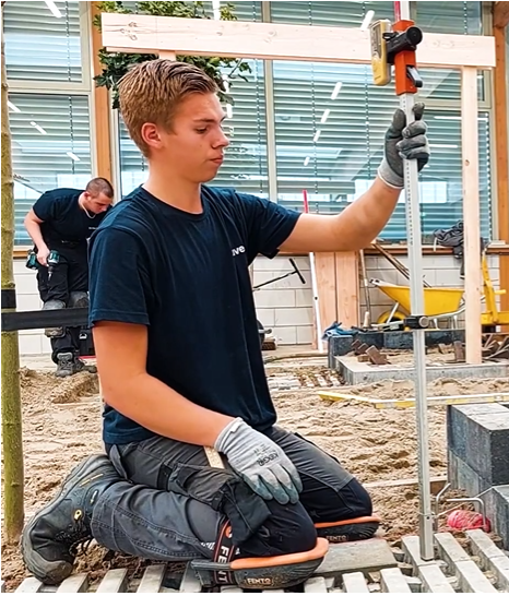 Een hoveniersstudent houdt lachend een vlag vast van Yuverta