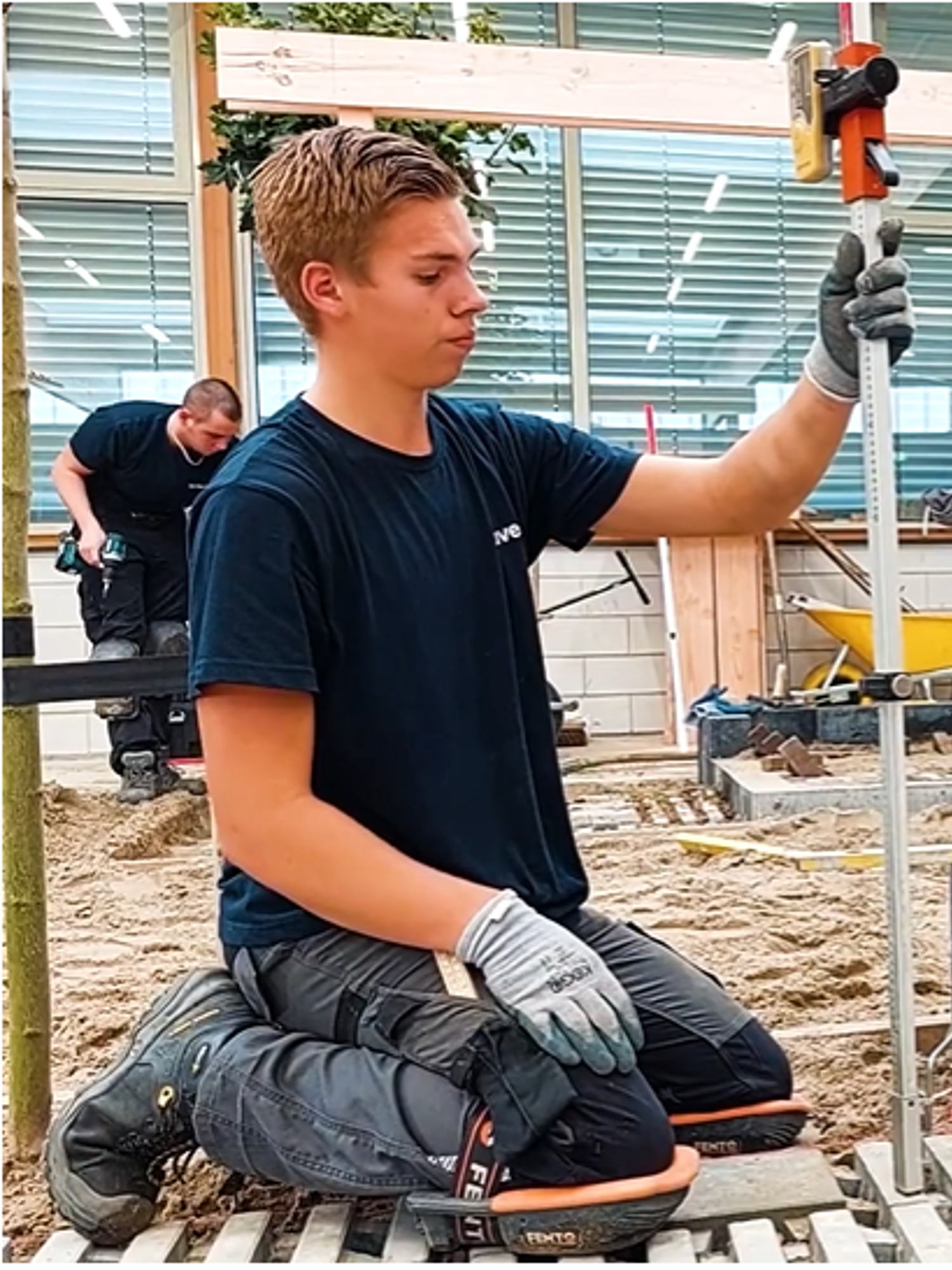 Een hoveniersstudent houdt lachend een vlag vast van Yuverta