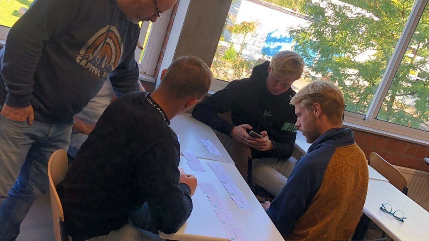 Docent leidt groep lachende studenten in klaslokaal