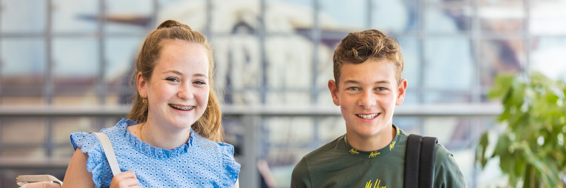 Twee lachende scholieren voor een schoolgebouw