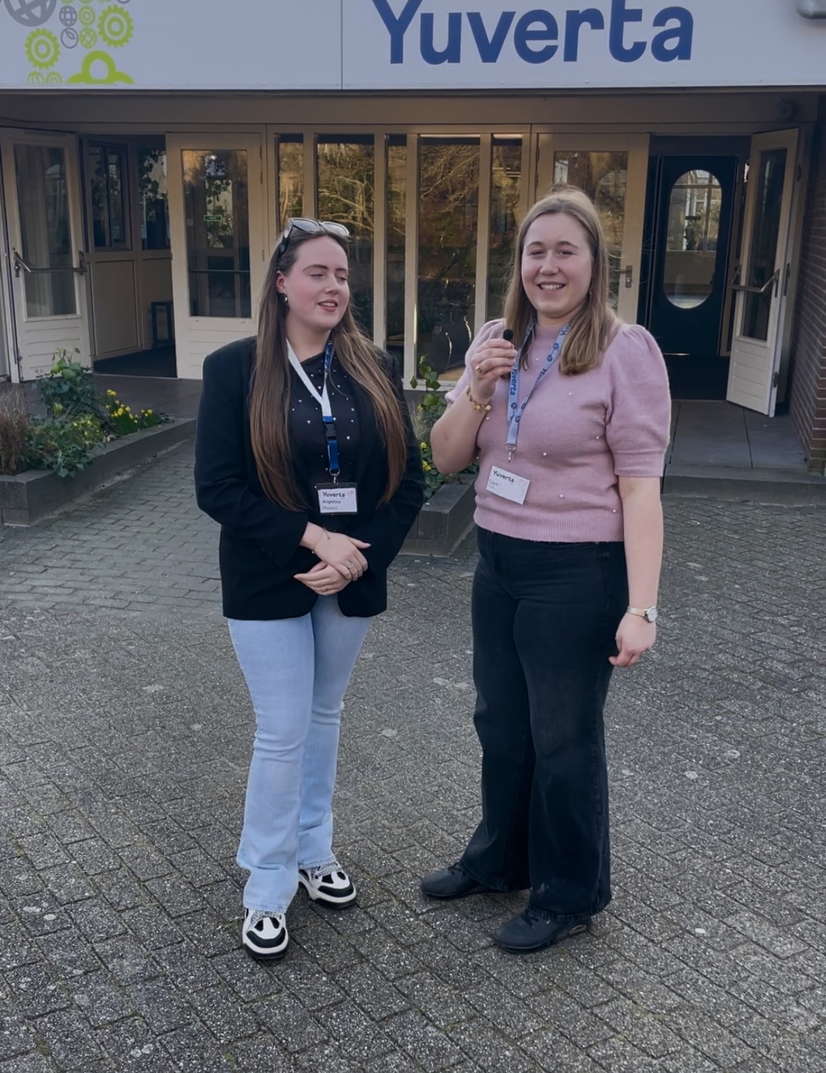 Een hoveniersstudent houdt lachend een vlag vast van Yuverta