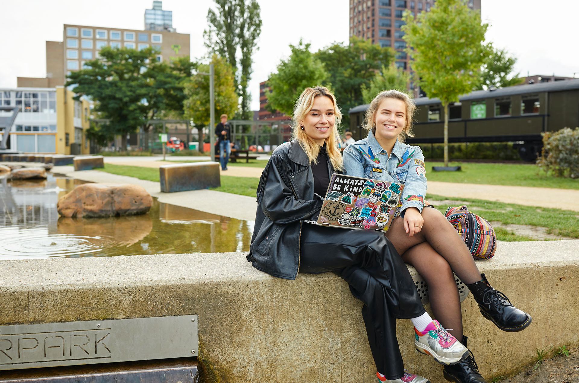 Twee studenten met een laptop, buiten voor een schoolgebouw