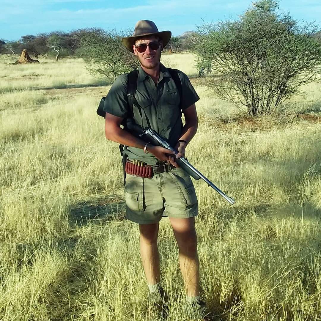 Jonge man met hoed en zonnebril in een natuurgebied in Afrika